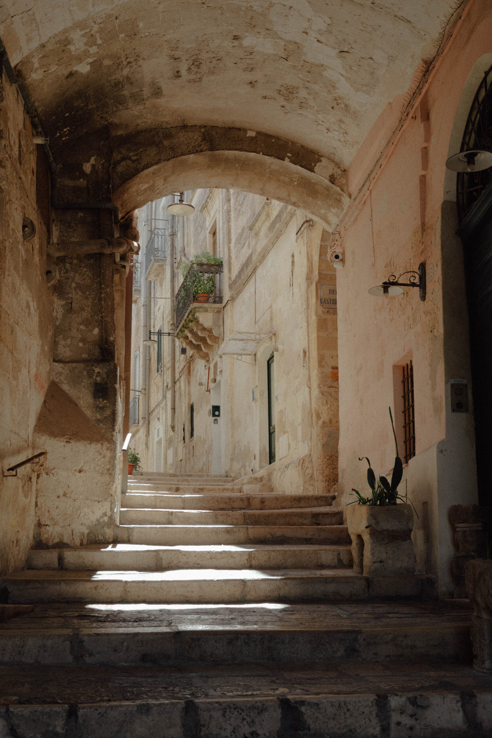 an arch and cobblestone alleyway in Matera's Sassi at sunset with warm golden light on stone walls